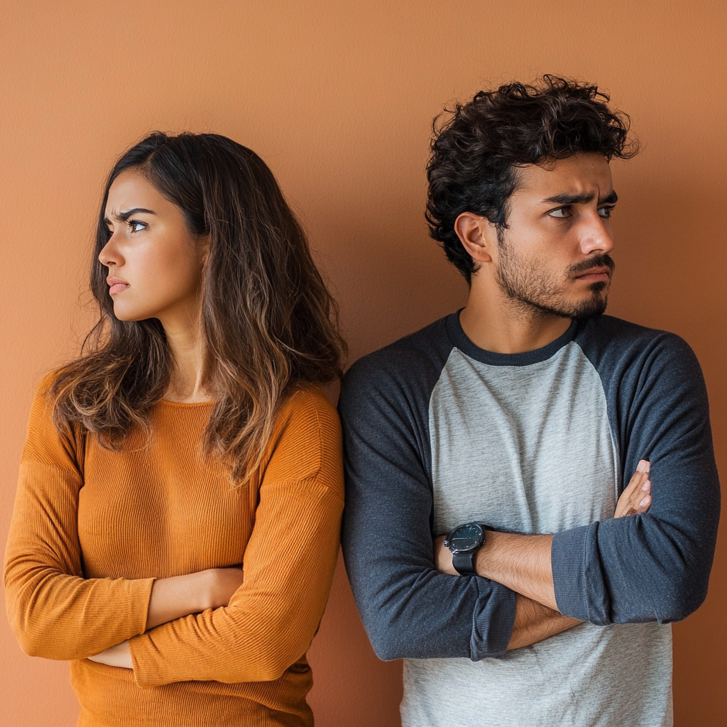 Casal com expressões tensas e braços cruzados, virados um de costas para o outro, ilustrando conflitos e ansiedade no relacionamento.